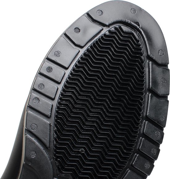 Close-up van de zwarte rubberen zool van een Chelsea regenlaars met een golvend profiel voor grip.