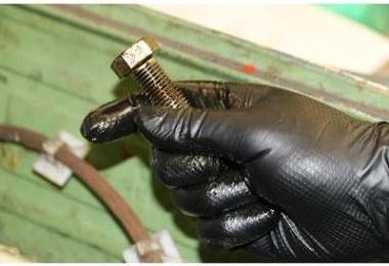 Een met zwart nitril Grippaz handschoen beklede hand houdt een met olie besmeurde bout vast.
