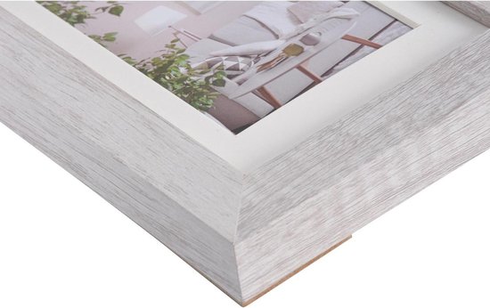 Een close-up van de hoek van een witte houten fotolijst met een crème passe-partout.