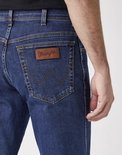 Detail van de achterzak van een blauwe Wrangler jeans met bruin label en Wrangler 'W' stiksels.