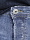 Close-up van de knoopsluiting van een blauwe spijkerbroek met tekst op de knoop.
