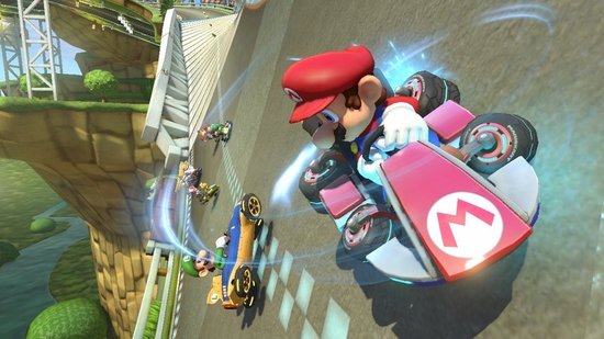 Mario en Luigi racen op een kartbaan in een berglandschap. De zon schijnt fel.
