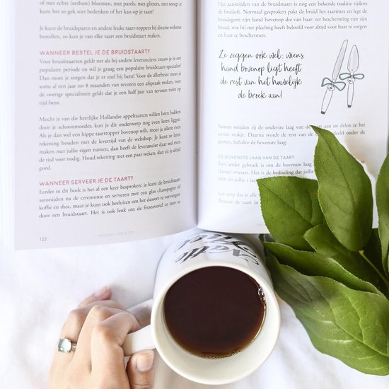 Een open boek met de tekst 'Trouwen doe je zo!' en een kopje koffie met een groene plant.