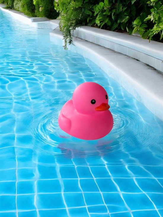 Een roze badeendje drijft in helderblauw zwembadwater, met zichtbare tegels onder water.