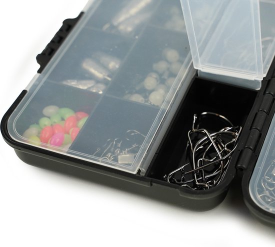 Close-up van een open tacklebox met vakjes gevuld met visaccessoires, waaronder haken en kralen.
