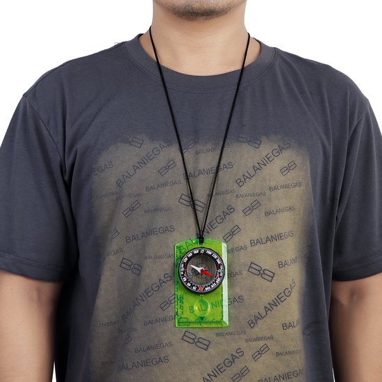Man met grijs shirt draagt een geel kompas met koord om zijn nek.