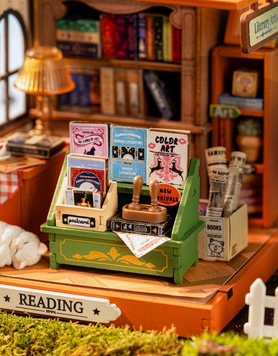 Close-up van de miniatuur boekenwinkel balie met boeken, ansichtkaarten, een stempel en kranten.