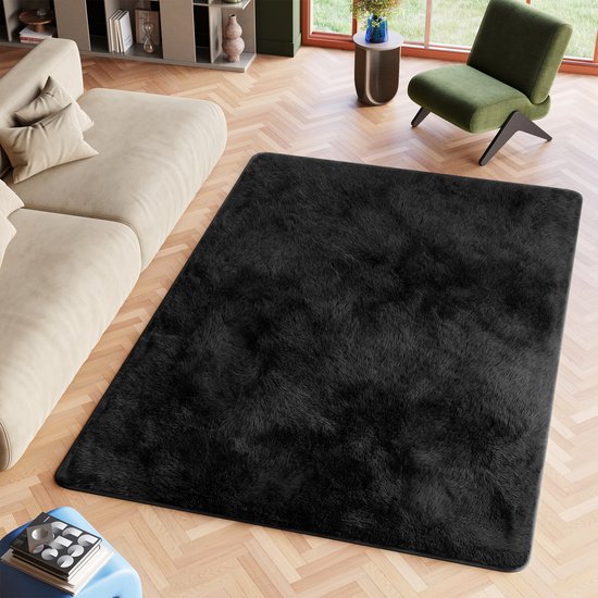 Tapis noir, à poils longs, shaggy et fluffy, dans un salon sur un parquet, à côté d'un canapé.