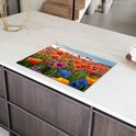 Een kookplaatafdekking met een bloemenveld vol klaprozen op een keuken aanrecht met marmeren blad.