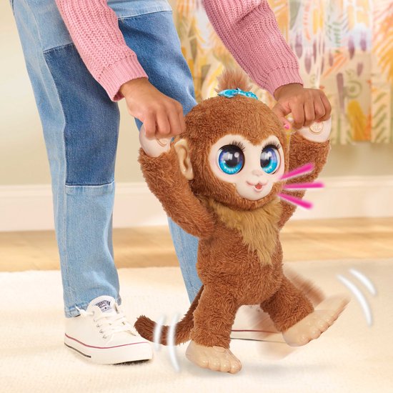 Kind houdt een bruine FurReal Peanut aap omhoog terwijl deze lijkt te springen.