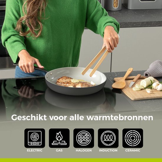 Een vrouw kookt een stuk vlees in een grijze koekenpan met houten tangen. De pan is geschikt voor alle warmtebronnen.