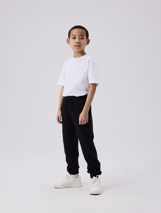 Jongen in een wit T-shirt en zwarte joggingbroek met koord.