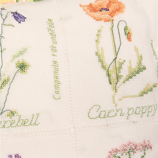 Détail d'une broderie en point de croix d'un coquelicot orange avec feuille et nom.