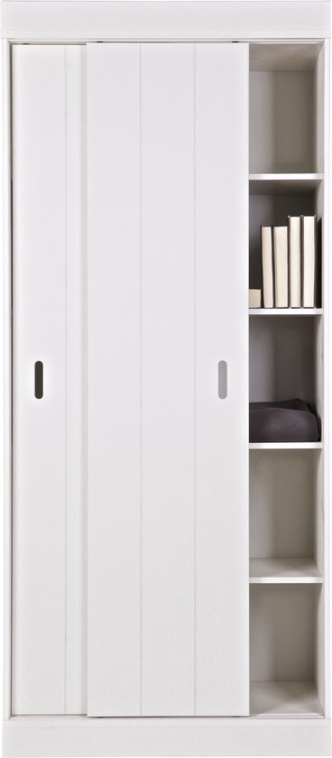 Witte kast met schuifdeur links en open vakkenkast rechts. Boeken en een deken liggen in de vakken.