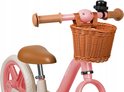 Close-up van het stuur van een roze loopfiets met bruine handvatten, mandje en bel.