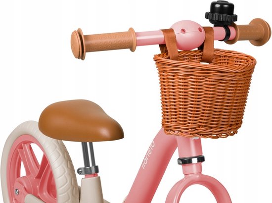 Close-up van het stuur van een roze loopfiets met bruine handvatten, mandje en bel.