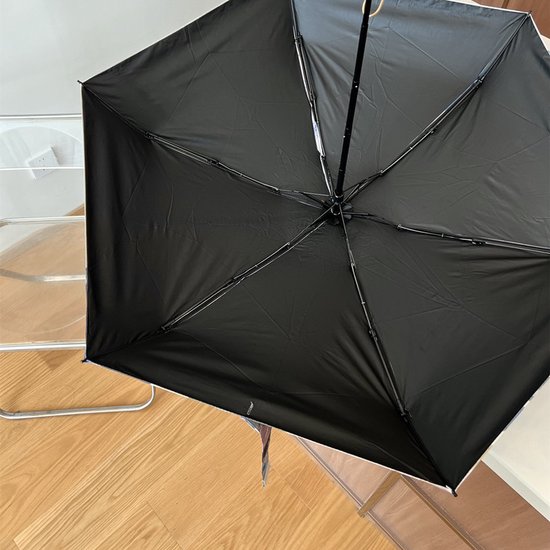 Binnenkant van een open, zwarte paraplu met metalen frame en baleinen.