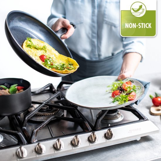Une omelette est glissée d'une poêle sur une assiette, à côté d'un bol de baies.
