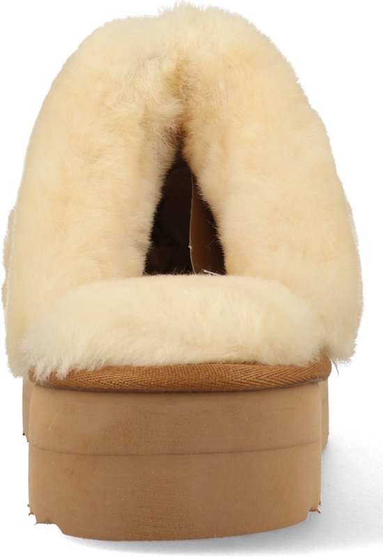 Achterkant van een cognac suède slipper met dikke schapenwollen voering en beige plateauzool.