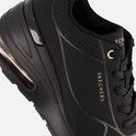 Detail van een zwarte Skechers sneaker met goudkleurige merknaam en veters.