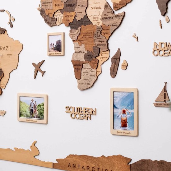 Drie houten fotolijsten op een wereldkaart: een stel in het groen, een gezin op een berg, een vrouw met rugzak bij zee.