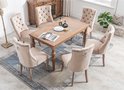 Eetkamer met zes beige fluwelen stoelen rond een houten tafel. Stoelen hebben knopquilting en metalen ringen op de rug.