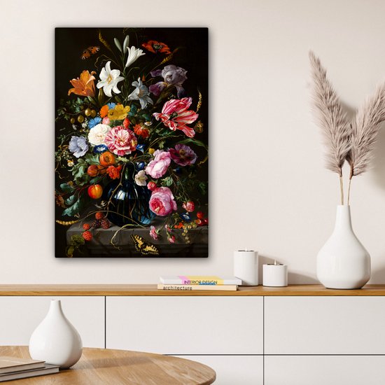 Un salon avec une armoire blanche et une table ronde, sur laquelle une peinture d'une nature morte florale est placée.