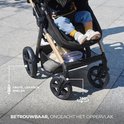 Close-up van de grote, lekbestendige wielen van een zwarte kinderwagen op een betegeld oppervlak.
