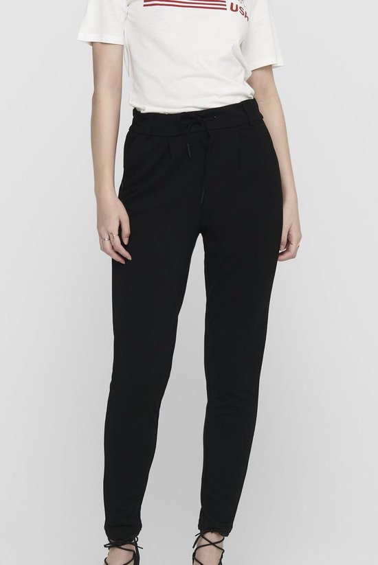 Model in zwarte broek met ceintuur en witte top. Close-up van de taille.