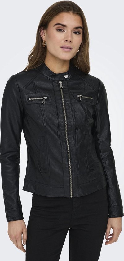 Vrouw in een zwarte faux leren bikerjack met rits middenvoor, ritszakken en zwarte broek.
