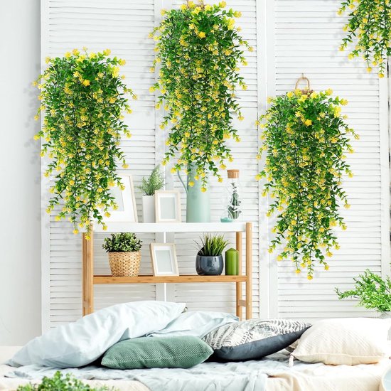 Drie hangende kunstplanten met groene bladeren en gele bloemen, gedecoreerd op een witte schuifwand.