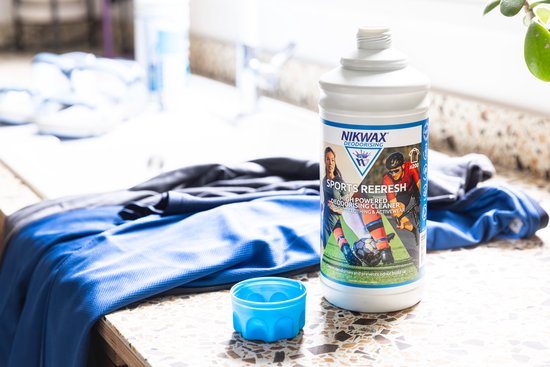 Fles Nikwax Sports Refresh met blauwe sportkleding en een blauw dopje ernaast.