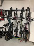 Garageopslag met een zwart fietsophangsysteem waarop fietsen, skateboards en gereedschap hangen.