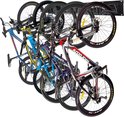 Vijf fietsen hangen aan een zwart ophangsysteem aan de muur.