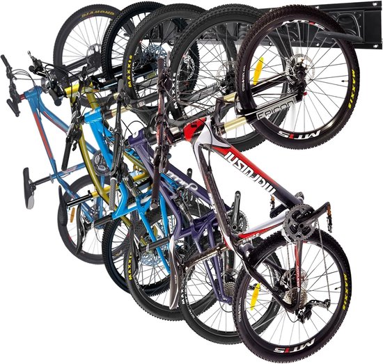 Vijf fietsen hangen aan een zwart ophangsysteem aan de muur.