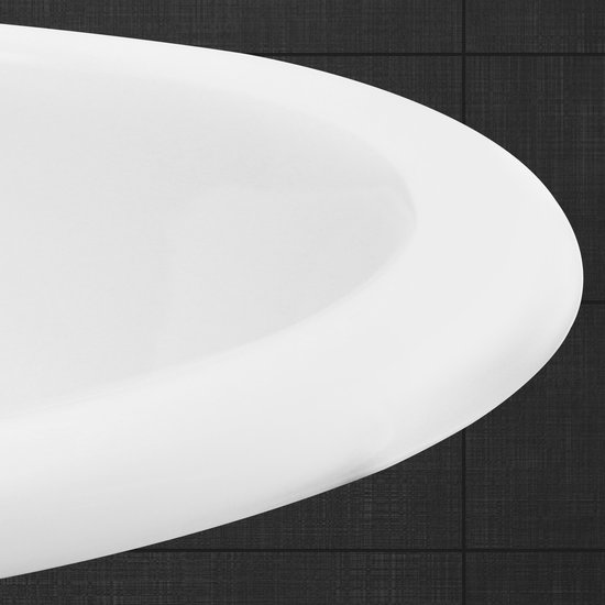 Détail du bord d'un lavabo ovale blanc sur un fond de carrelage sombre.