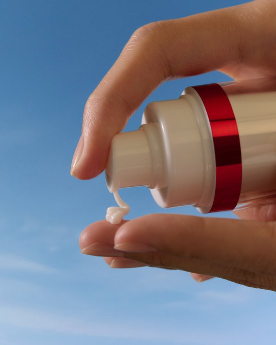 Hand drukt pompje van Nivea Luminous630 serum, een witte crème druppelt op de vinger.