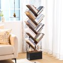 Boekenkast in boomvorm met houten takken, gevuld met boeken, in een lichte woonkamer met een bank en een raam.