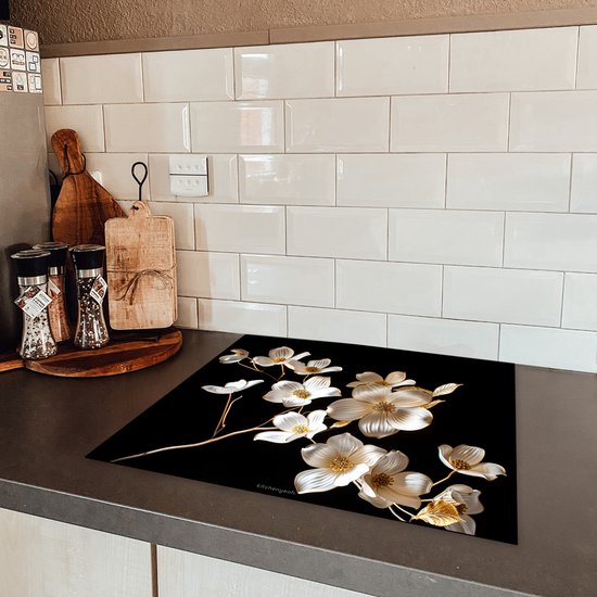 Glazen snijplank met witte en gouden bloemen, op een keukenblad.