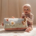 Baby zit met een activiteitenboek in de vorm van een driehoek met bloemen, vogels en een vosje.