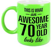 This is what an awesome 70 year old looks like cadeau mok / beker - 330 ml - neon groen - verjaardag - kado koffiemok / theebeker