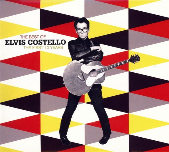 Elvis Costello met akoestische gitaar voor geometrisch patroon. Tekst: THE BEST OF ELVIS COSTELLO THE FIRST 10 YEARS.
