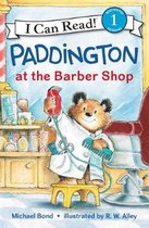 Paddington, de beer, staat op een geel krukje in een kapsalon en houdt een scheerapparaat en kam vast.