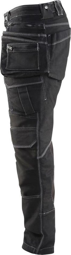 Zijkant van zwarte werkbroek met veel zakken, verstevigd kruis en wit stiksel.