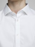 Gros plan sur le col et la fermeture boutonnée d'une chemise blanche.