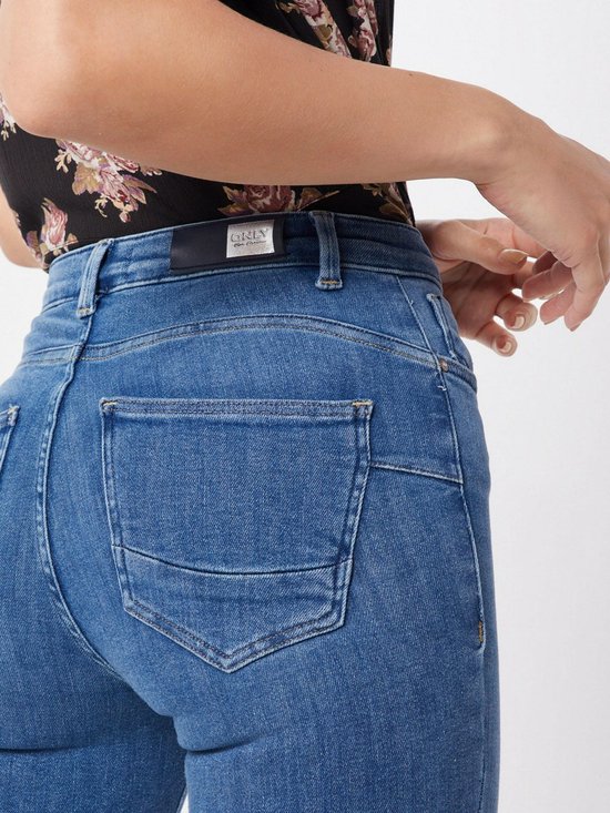 Close-up van de achterkant van een blauwe skinny jeans met middelhoge taille. Merklabel zichtbaar.