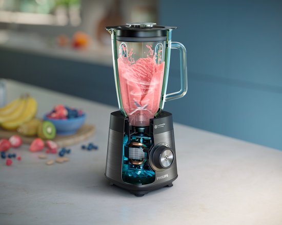 Philips blender met transparante kan, motor zichtbaar. Vruchten op aanrecht.