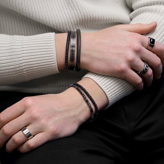 Personen met verschillende ringen en armbanden, waaronder kralenarmbanden en een ring met zwarte steen.
