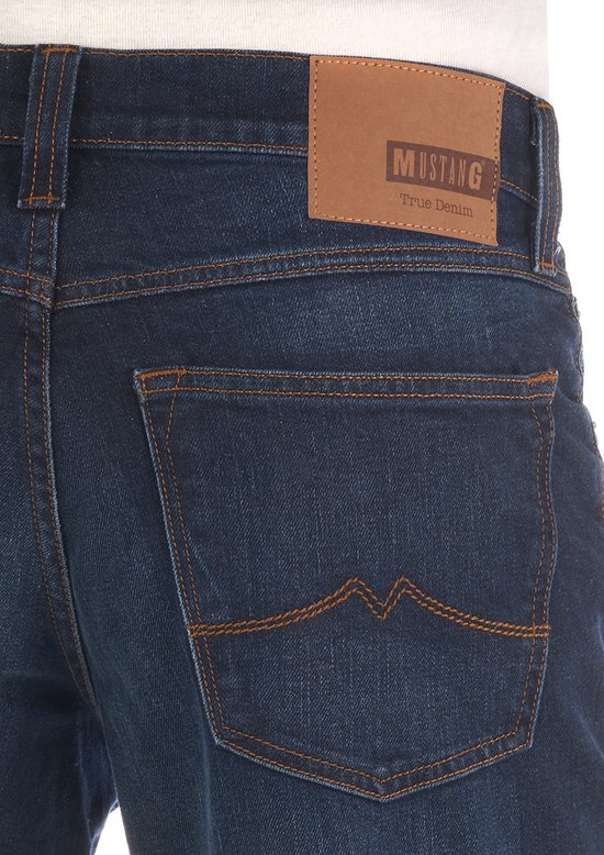 Achterkant donkerblauwe jeans met oranje stiksels en bruin Mustang 'True Denim' label.