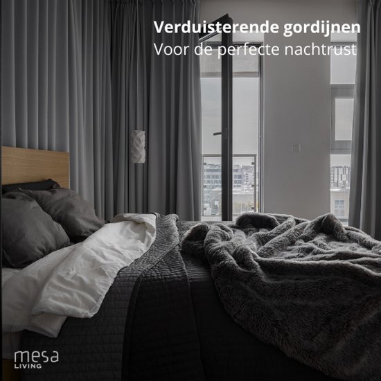 Donkergrijze verduisterende gordijnen in een slaapkamer met een bed.